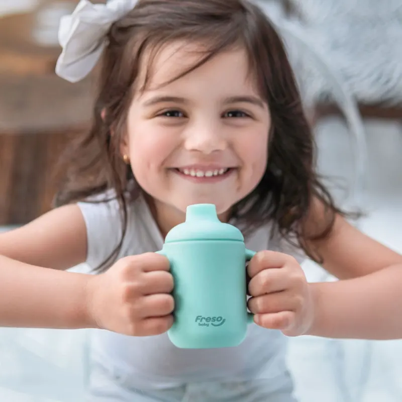 Criança sorrindo com o copo Freso verde
